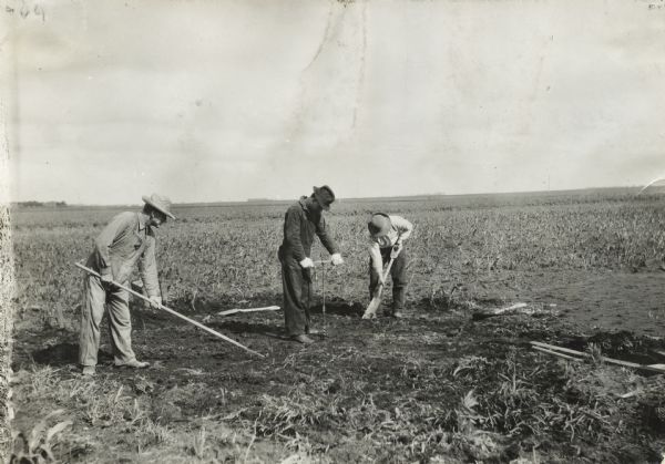 Three men working at a site for a new pit silo on an International Harvester demonstration farm.