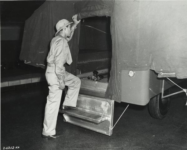 Original caption reads: "E.C. Prince, photographer member of the Gatti-Hallicrafters Expedition, is shown entering a Higgins camp trailer to be used in Africa."