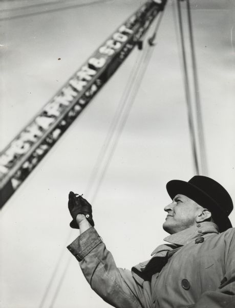 Original caption reads: "Loading Gatti-Hallicrafter Expedition equipment, including 8 International trucks on the 'S.S. Pilgrim' at the American South African Line Pier... Commander Gatti is shown in hat and raincoat."
