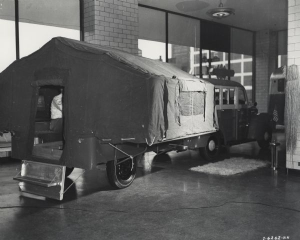 Original caption reads: "International motor trucks used by Gatti-Hallicrafters Expedition shown inside and outside of Manhattan showrooms, International Harvester Company, motor truck division." A man can be seen sitting in the trailer.