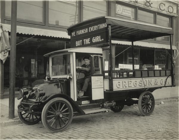 International model G truck used by Gregson and Co. Text on the truck reads: "we furnish everything but the girl."