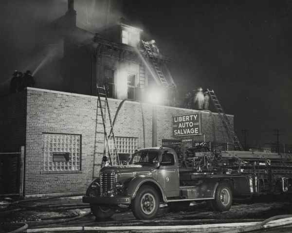 International KBR-10 truck belonging to St. Louis Fire Department at the scene of a fire. Original caption reads: 'KBR-10 149" wheelbase, double reduction rear axle 7.049 to 1 gear ratio, F-54 O.D. transmission 9.00x20 10-ply tires. Red 401 Engine.'