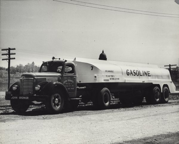 International KB-8 truck used as oil tanker. The name on the truck reads: "John Groner, Motor Carrier, Inc.; Jefferson City, MO." A dome, possibly the State Capitol building, is in the far background.