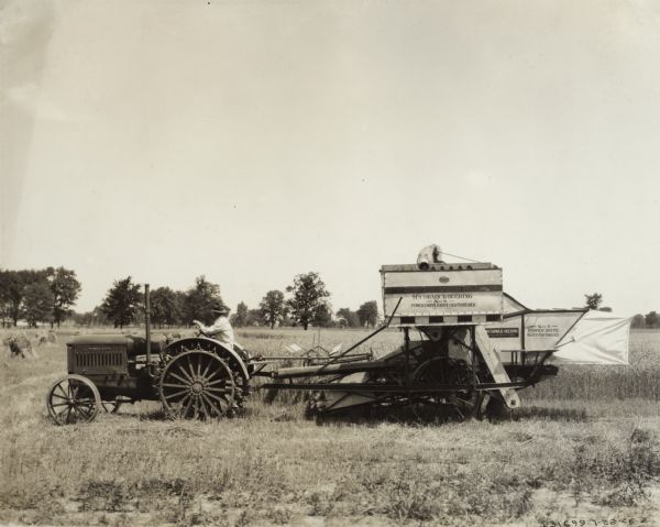 Farmer harvesting grain with a McCormick-Deering tractor and a No. 8 harvester-thresher (combine). Original caption reads: "Equipped with grain tank this economical one-man outfit did much to popularize the combine method of grain harvesting in the central, eastern, and southeastern states."