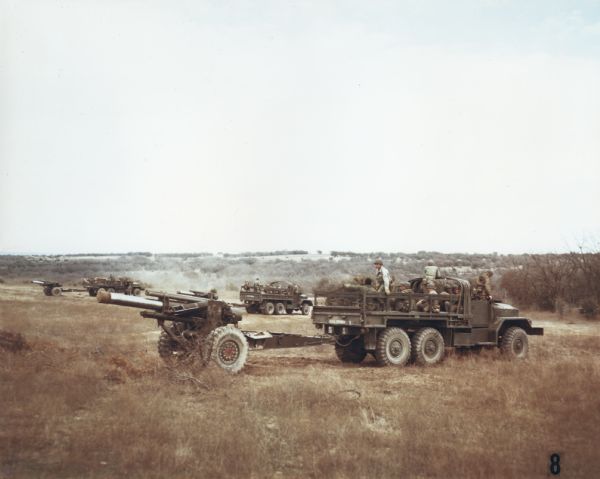 Color photograph of M-41 and M-54 cargo vehicles servicing and transporting 155-mm howitzers with 10-gun crews. The trucks belonged to the 73rd Armored Artillery Battalion. The specifications for the M-41 are as follows: 179" WB Truck, Cargo, with 14.00 x 20 front & single rear tires; and for the M-54: 179" WB Truck, Cargo, with 11.00 x 20 front & dual rear tires.