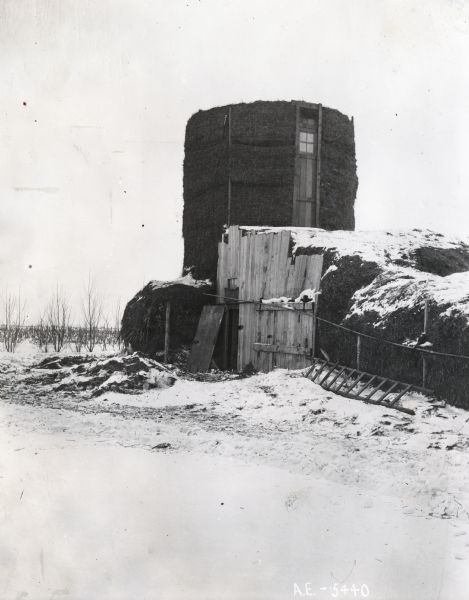 View of a silo readied for winter storage with straw held against the outer walls with wire netting.