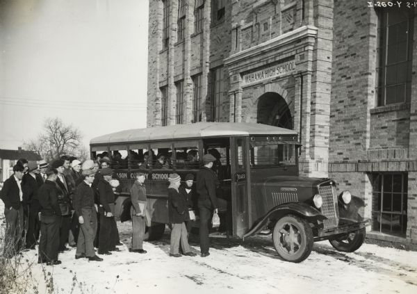 Group of male students boarding an International school bus outside Wahama High School. Female students are already sitting on the bus.
