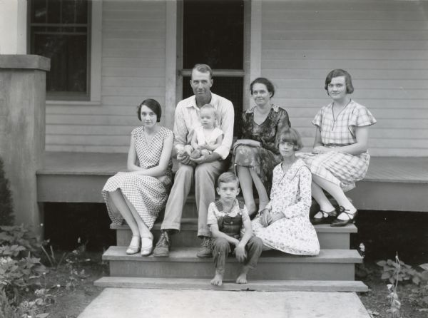 Group portrait of Josh Gillespie sitting with his wife and children on the steps of a farmhouse. Gillespie was foreman at International Harvester's Montgomery demonstration farm.