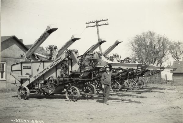 A man is standing with McCormick-Deering all steel stationary threshers. Decals and/or stencils are on the machines. Original caption reads: "Martin R. Anderson, Cambridge Illinois."