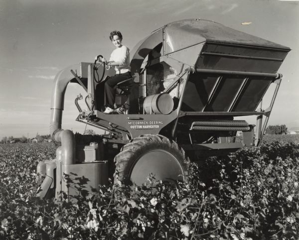 Dorothy Hutchison operating a McCormick-Deering H-10-H cotton picker in a field. Stencils and/or decals are on the machine.