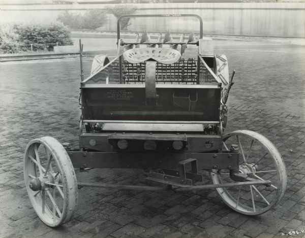 View of the front of a McCormick-Deering manure spreader. A stenciled warning on the machine reads: "Caution do not throw in gear while team is in motion."