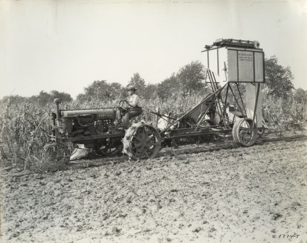 McCormick-Deering one-row tank corn picker pulled by a Farmall Regular tractor in a field.  Stencils are on the picker.