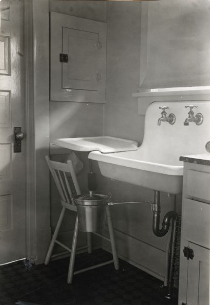 A metal sanitary garbage pail attaches underneath the kitchen sink and pipes at the farmhouse of Miss Lella Gaddis.