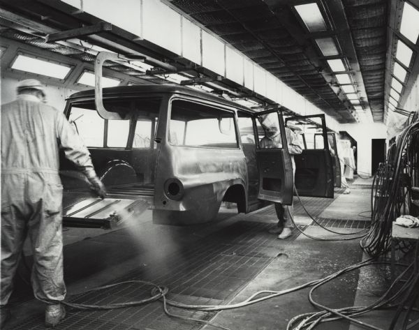 Factory workers are painting Travelall bodies on an assembly line at International Harvester's Springfield Works. The original caption reads, in part: "International Travelall bodies receive their finish coat in one of the Springfield assembly plant's seven paint booths."