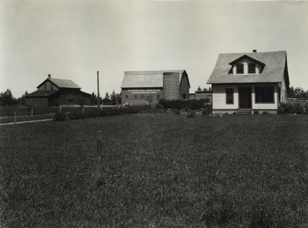 View from lawn of farm buildings, farmhouse and grounds at an International Harvester demonstration farm.