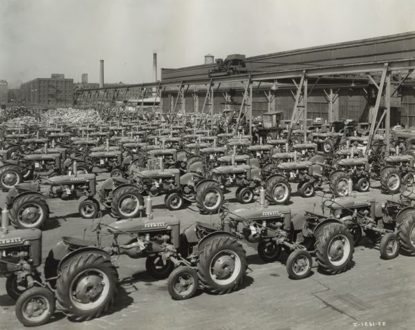 Slightly elevated view of rows of Farmall A and Farmall B tractors in the Chicago Tractor works loading yard. Original caption reads: "From: International harvester Company, 180 N. Michigan Ave., Chicago Ill. April 24th, 1941. A lineup of Farmall-A and Farmall-B tractors in the loading yard of the Chicago Tractor Works prior to shipment. Fully equipped and tested, the tractors are here ready to be shipped to distribution points from which they will go directly to farmer users."