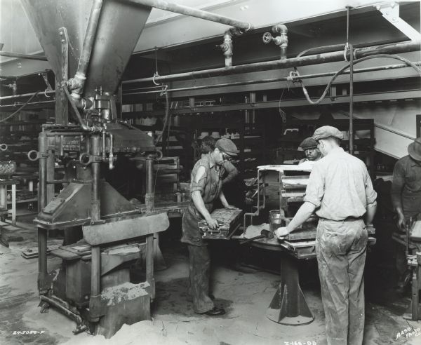 Men at the International Molding Machine Company factory working with core boxes after removal from the core blower.