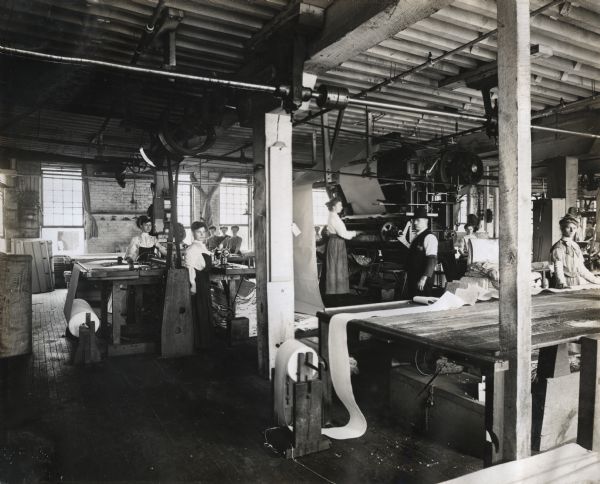 Female and male factory workers operating machines in the canvas department at International Harvester's Deering Works. The canvas was likely used for grain binders, harvester-threshers (combines) and push machines.