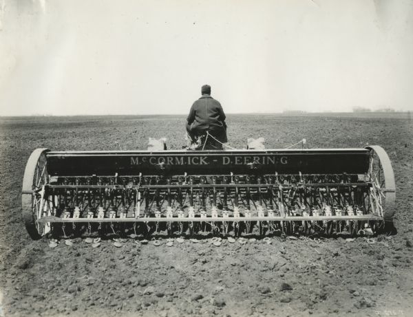 Man uses a Farmall Regular tractor to pull a McCormick-Deering grain drill in a field. Original caption reads: "John Maher- Fargo, North Dakota. Farmall & 28-6 grain drill."