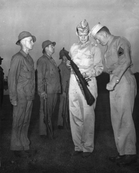 Lieutenant Colonel Van Syckle inspects the rifle of soldier Morris J. Fortin, formerly an employee of International Harvester's Salina branch.