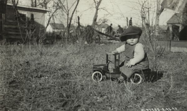 Joseph Byron Young playing with a toy International truck in the yard of a farm.