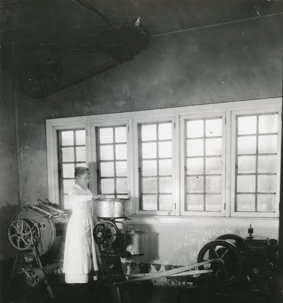 Mrs. Irving Bielby operating a cream separator run by a gasoline engine at Babcock farm.