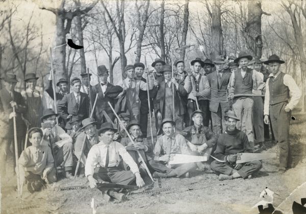 Group of boys outdoors with gardener E.E. Harris. Original caption reads: "Boys of the Onalaska Agricultural School, with rakes and forks, saws and other implements, ready for a day in the field." 