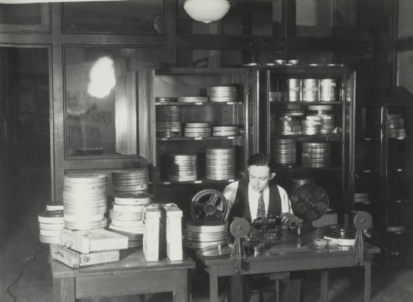 Agricultural Extension worker repairing reels of film in a storage room.