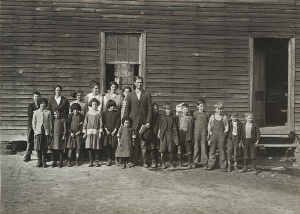Class of students and teacher(?) standing outside a rural school known as the Blackjack School.