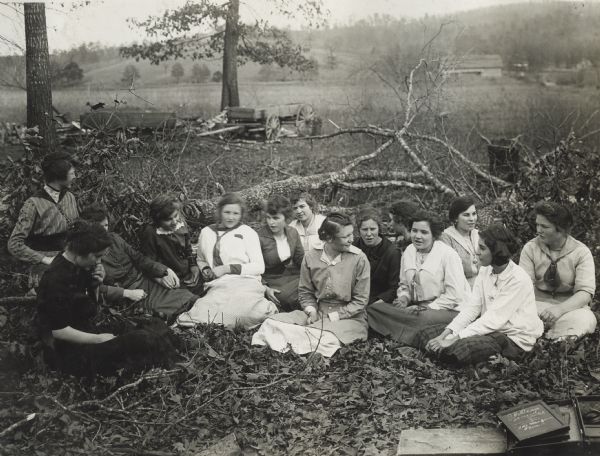 Group of school girls sitting outdoors in the grass. Original caption reads, in part, "this group of young ladies at La Wier school near Tallidega, Ala. were caught while seated in a group among some fallen trees singing some of their favorite school-day songs."