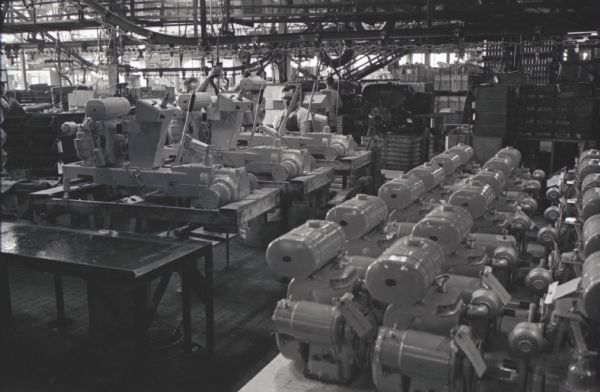 Cub Cadet engines and chassis on the factory floor of International Harvester's Louisville Works. Two men work in the background.
