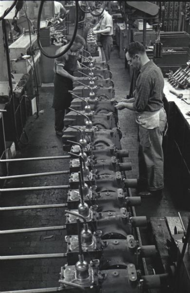 Elevated view of factory workers piecing together Cub Cadet parts along an assembly line at International Harvester's Louisville Works.