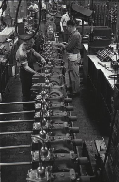 Elevated view of factory workers assembling pieces of the Cub Cadet lawn tractor while standing on either side of an assembly line at International Harvester's Louisville Works.