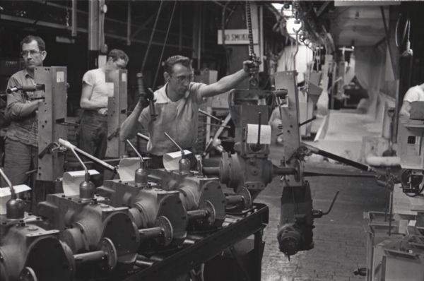 Factory workers use a ceiling-mounted conveyor while assembling Cub Cadet lawn tractors at International Harvester's Louisville Works.