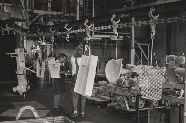 Factory workers attach Cub Cadet parts to a chassis as they arrive along a ceiling-mounted conveyor at International Harvester's Louisville Works.