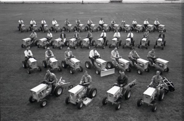 Elevated view of men, possibly dealers or buyers, sitting on International Harvester Cub Cadet lawn tractors in four rows. The machines were manufactured at the company's Louisville Works.