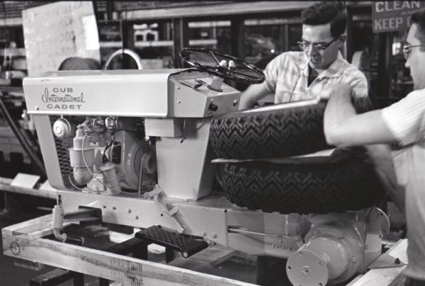 Two factory workers ready a Cub Cadet lawn tractor for boxing and shipping at International Harvester's Louisville Works.  The machines were packaged with separate tires for assembly at the dealership.