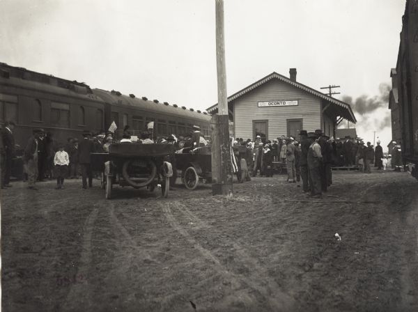 Group of people and automobiles gathered around a train station at a stop of the "Union Pacific Nebraska Preparedness Special Campaign."