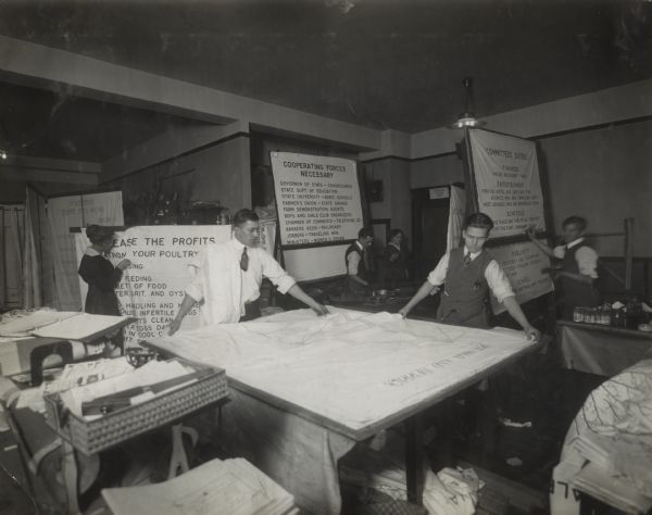 Group of male and female workers assembling International Harvester Agricultural Extension lecture charts.