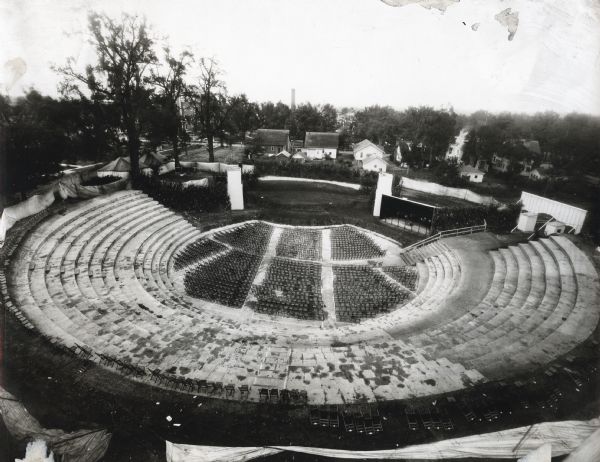 Elevated view of a Greek amphitheater. Residences and other buildings are in the background.
