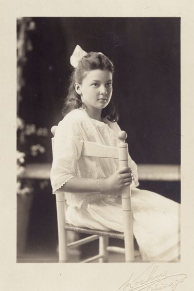 Portrait of May Morrill Dunn wearing white dress and seated on a chair.