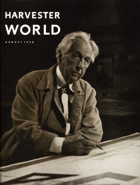 Frank Lloyd Wright posing on the cover of "Harvester World" magazine. Wright is sitting at a desk at Taliesin.