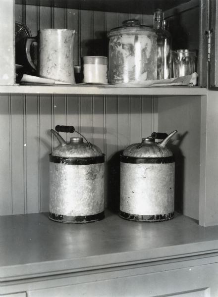 Gasoline and kerosene cans stand side by side on a shelf at International Harvester's Hinsdale experimental farm, demonstrating a farm hazard.
