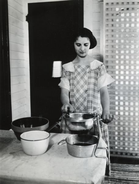 A woman using a Dilver (fruit press) to juice fruit into a metal bowl on a tabletop.