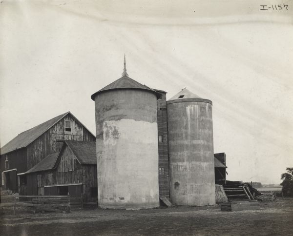 Two cement silos next to barns.