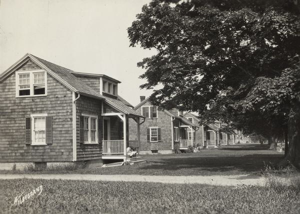 Farm employee housing. Original caption reads: "employees cottages on Briarcliff Farms." Children are sitting on the porch of the house in the foreground.