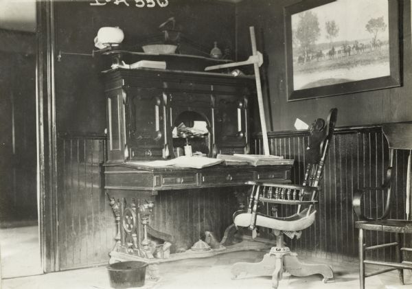A wooden chair on casters sitting in front of a large office desk, possibly at an International Harvester branch house, dealership or factory.