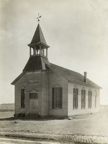 Exterior of a town hall originally built in 1896 as a church in rural Orange Township, Black Hawk County, Iowa. There is a weather vane on top of the steeple or bell tower.