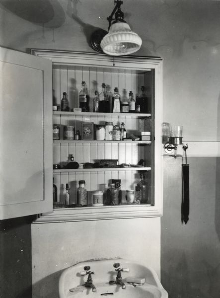 View of an opened medicine cabinet above a sink at International Harvester's Hinsdale experimental farm.