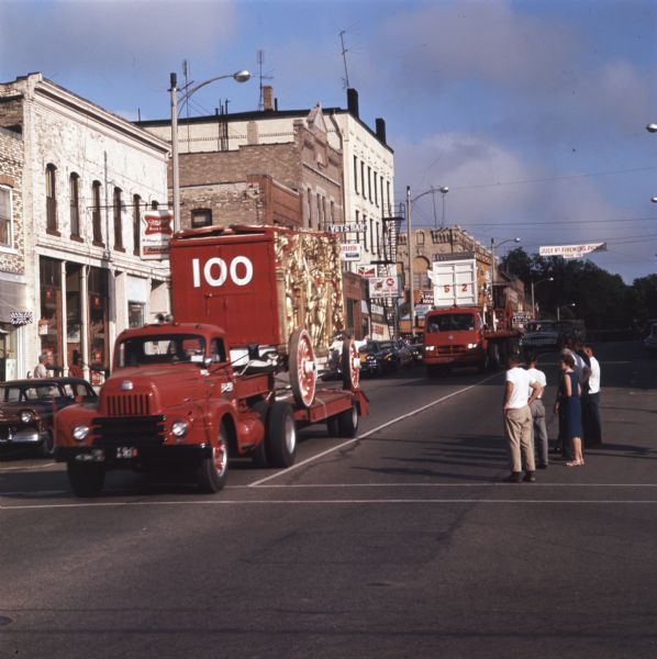 A group of men and women look on as a parade of circus wagons passes through downtown streets, carried on the beds of International trucks. The 25-piece parade originated at Circus World Museum in Baraboo and ended in Milwaukee.